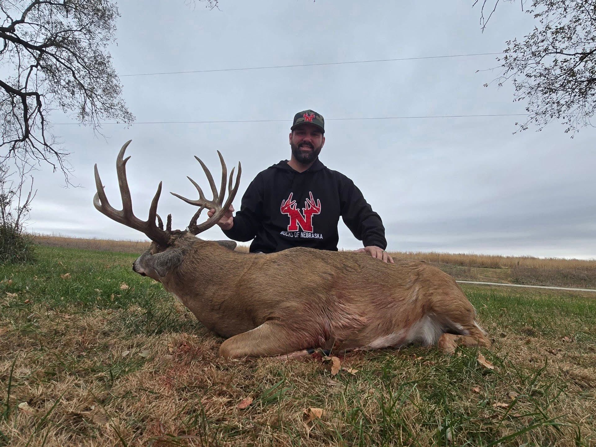 Cody Neer with a trophy Nebraska whitetail buck wearing Bucks of Nebraska hoodie